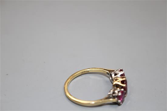 An 18ct and three stone ruby and garnet?? set dress ring, size M, gross 2.7 grams.